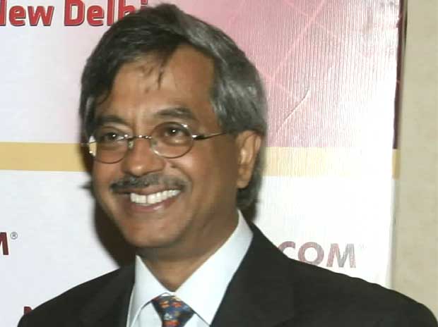 Pramod Bhasin smiling in a suit and glasses in an archival press photograph
