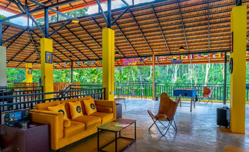 An open-sided hostel common room with yellow seating and tables