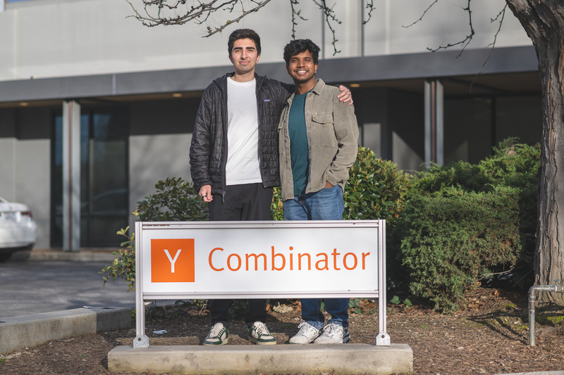 Arman Rafati and Praneeth Guduguntla standing together behind a Y Combinator sign outdoors
