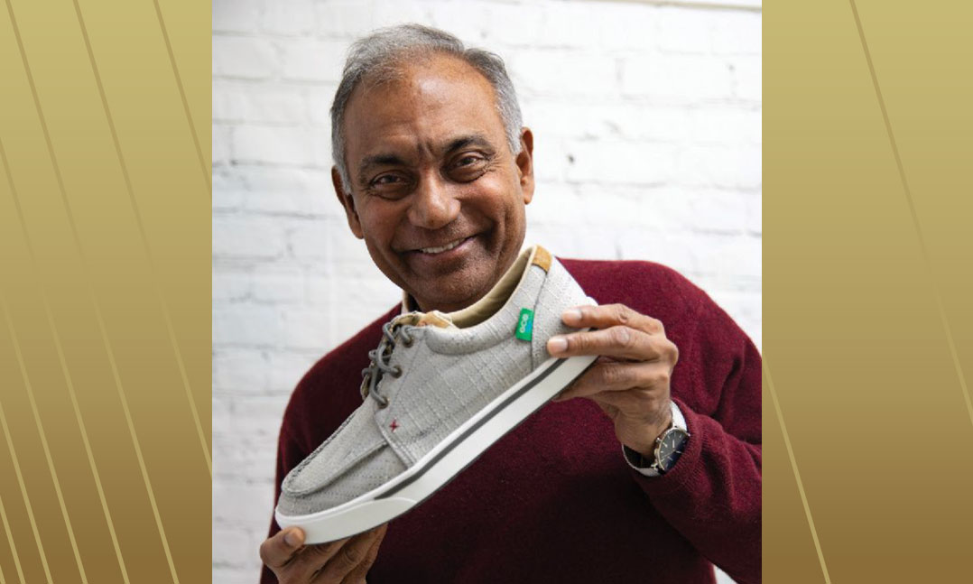 Prasad Reddy smiling while holding a gray casual shoe at Twisted X headquarters