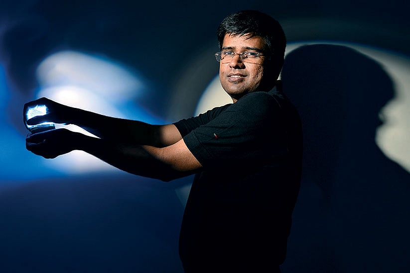 Prasanth Gopalakrishnan holding a light in a blue-lit press photograph