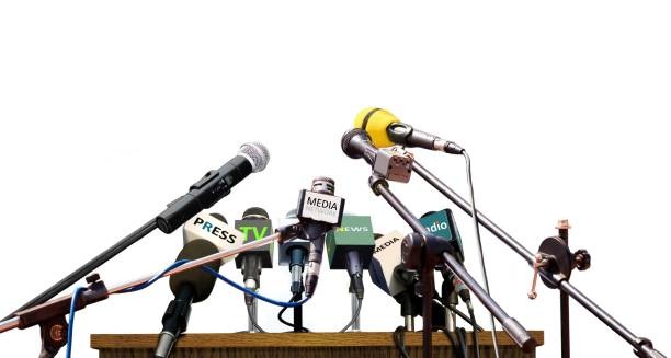 A group of news, radio and television microphones aimed at a lectern