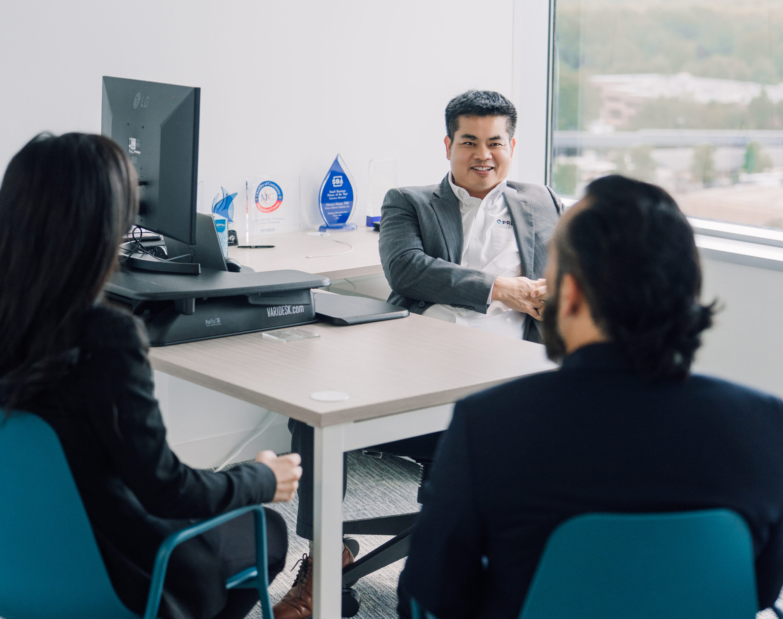Precise Software founder Zhensen Huang speaking with colleagues in the Rockville office