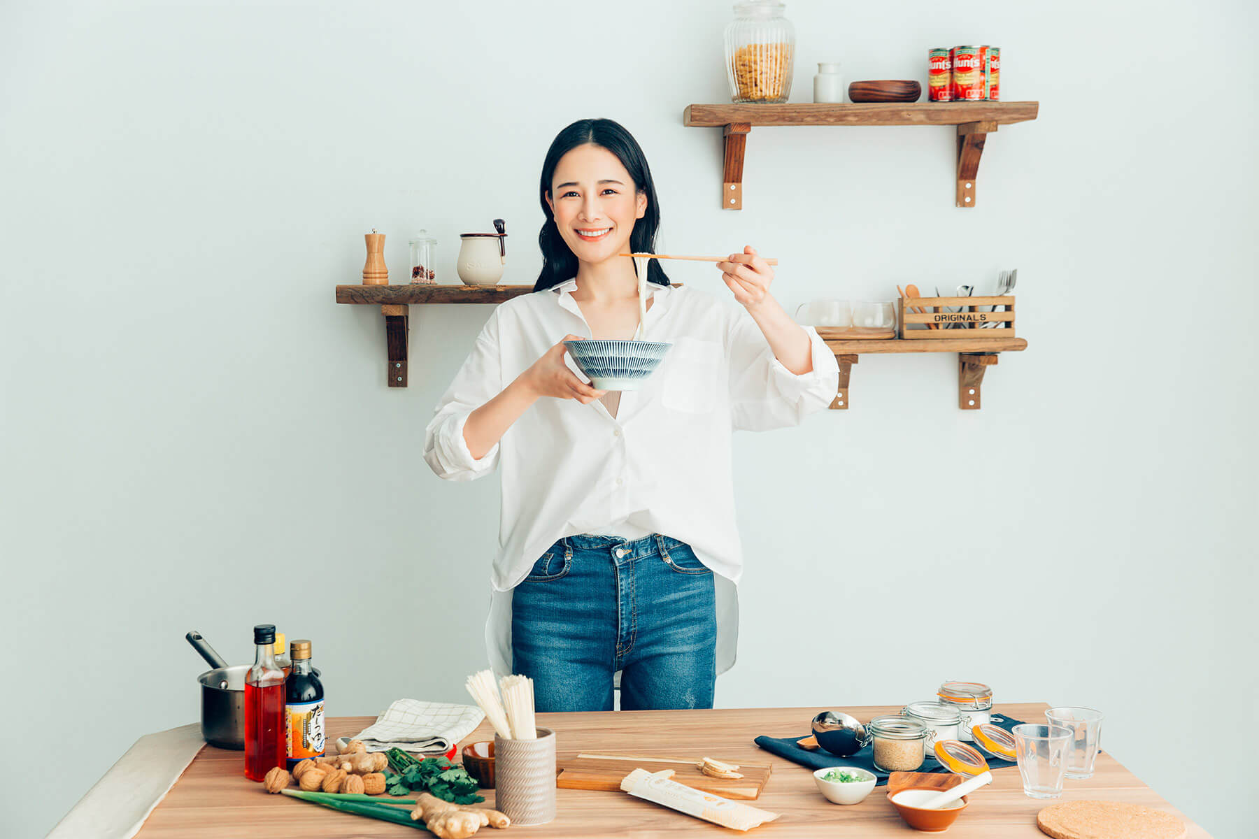 Food creator Chien-Chien holding a bowl and chopsticks at a kitchen counter