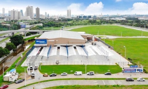 Aerial view of a PriceSmart warehouse club, its parking area and surrounding development