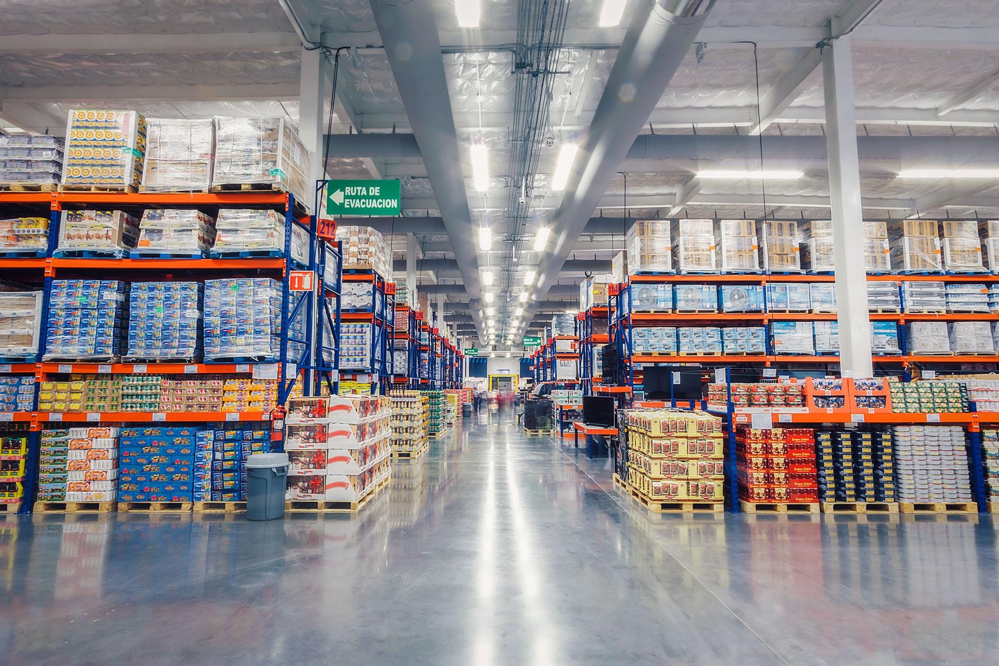 Tall pallet racks and bulk merchandise lining a wide PriceSmart warehouse aisle