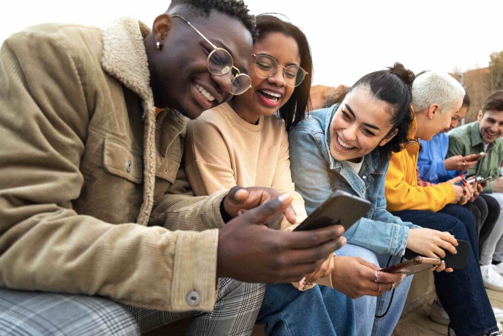 A group seated outdoors looking at smartphones