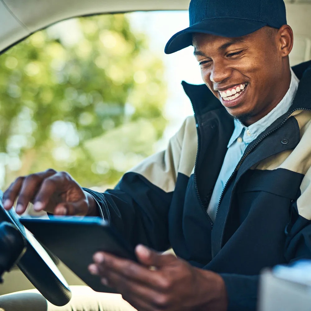 Primis promotional photograph of a delivery driver using a tablet in a vehicle