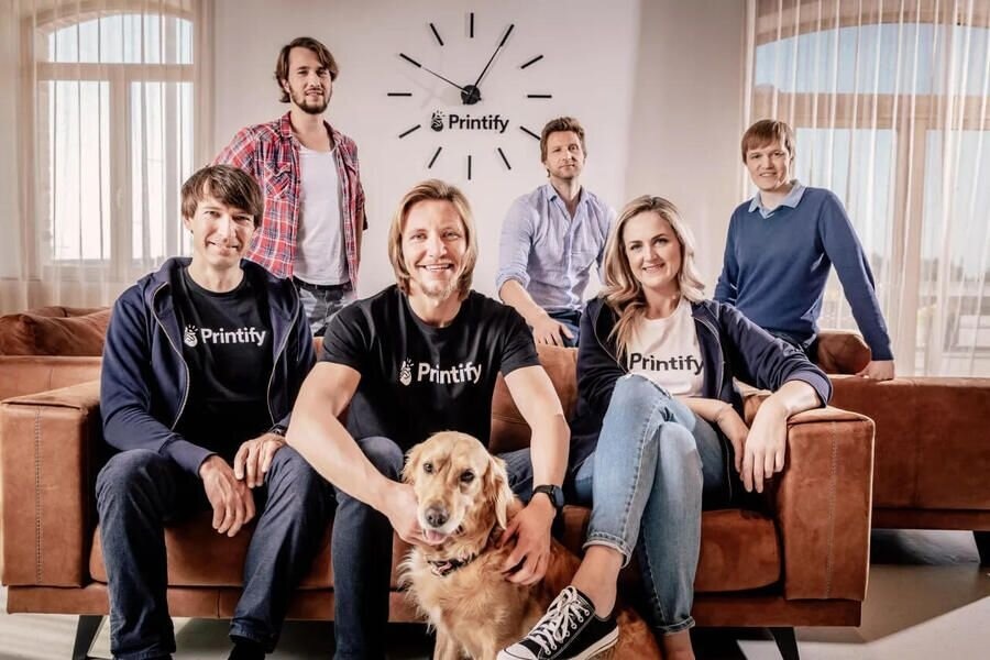 An archival Printify team portrait around a sofa with a dog in front