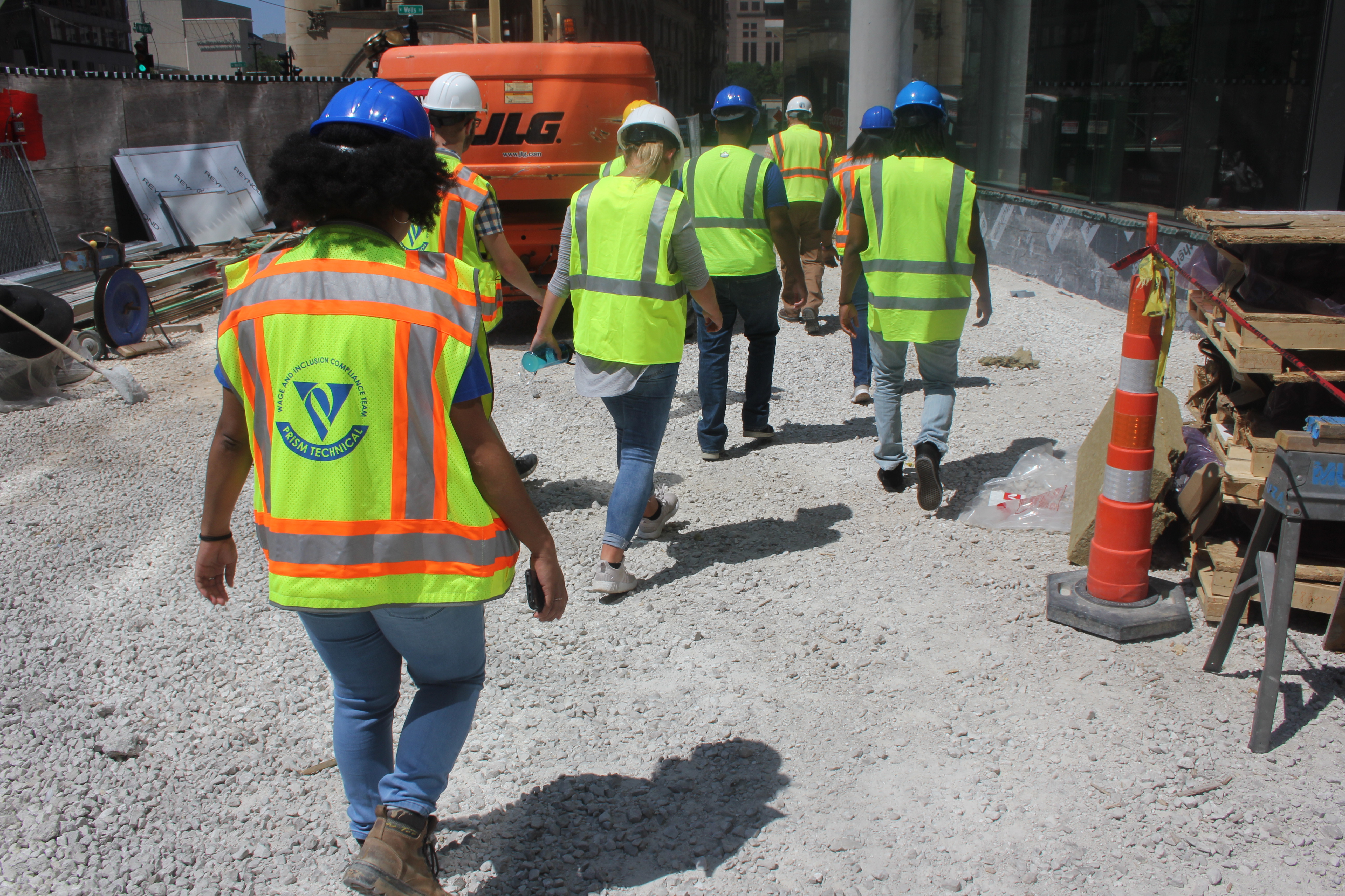 Prism Technical staff and visitors in safety vests walking through a downtown construction site