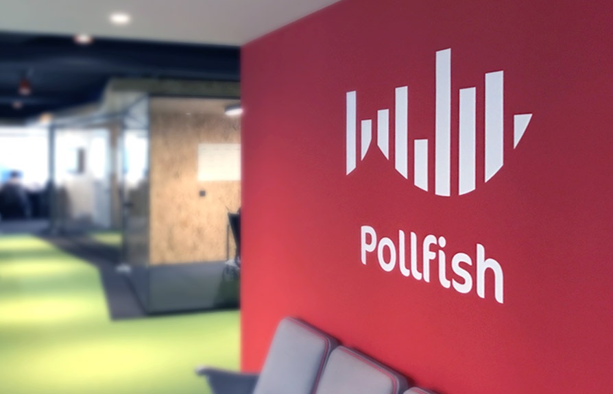 Pollfish office with a red feature wall, white wordmark and glass meeting rooms