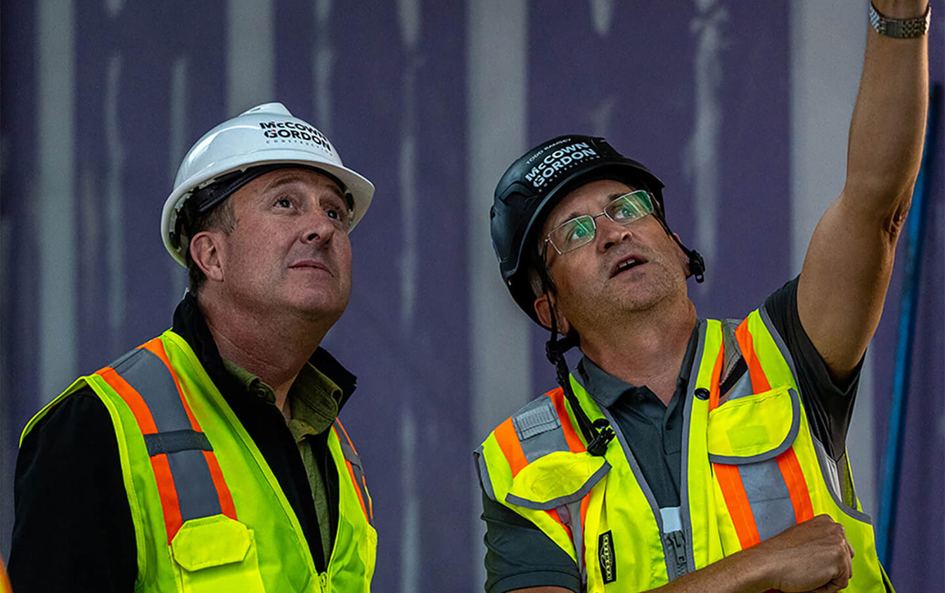 Two construction professionals in hard hats inspecting work on site
