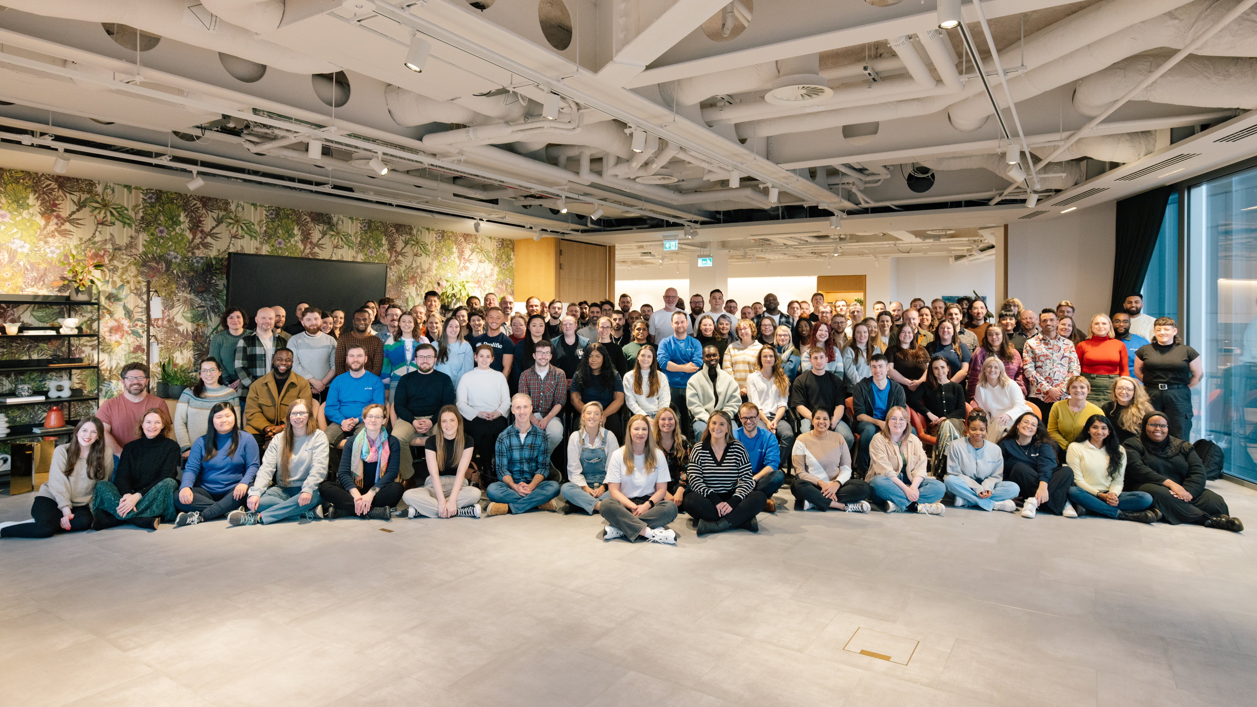 Prolific colleagues gathered for a group photograph in a large meeting space