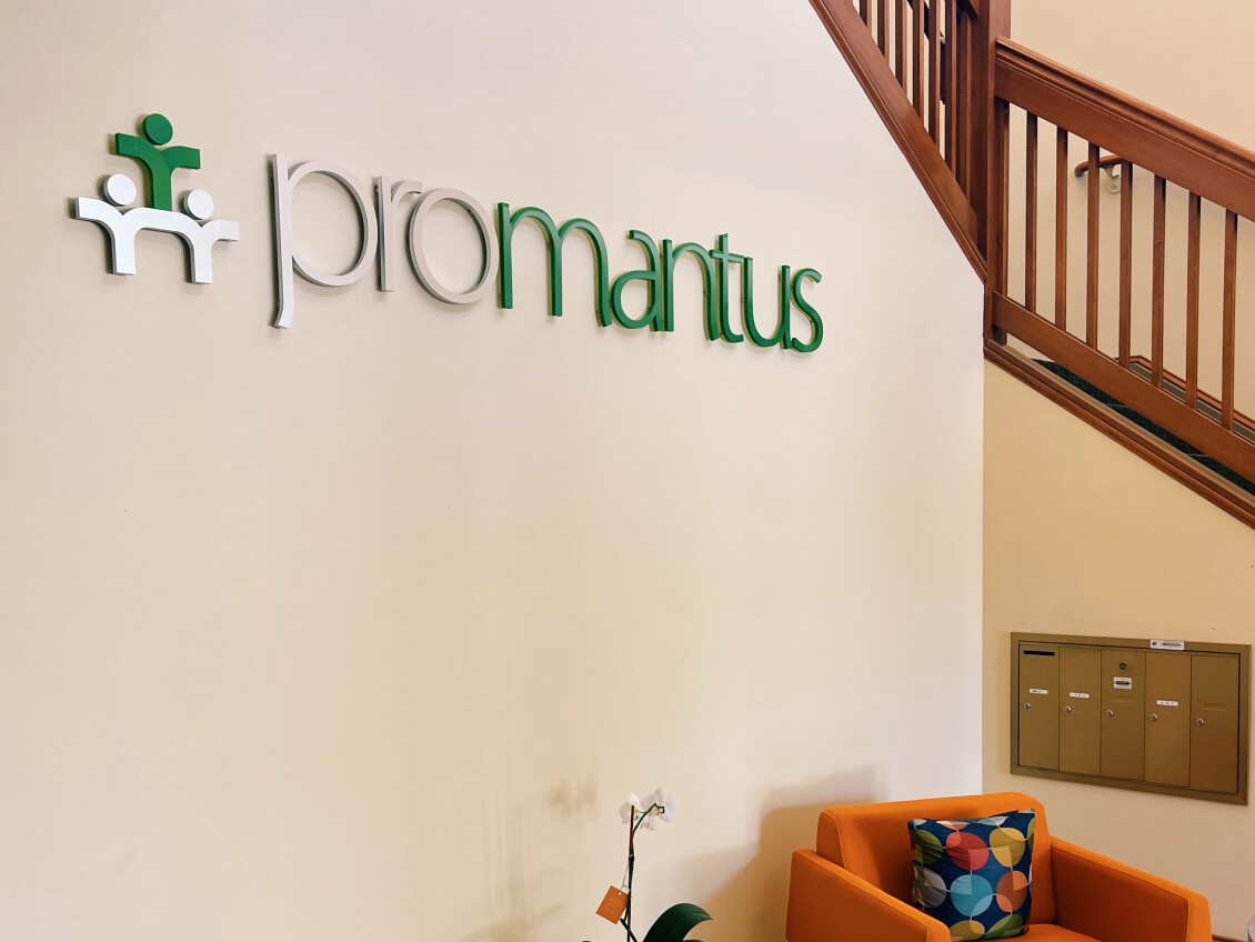 Promantus’s Raleigh office, with a wall sign, staircase and orange chair