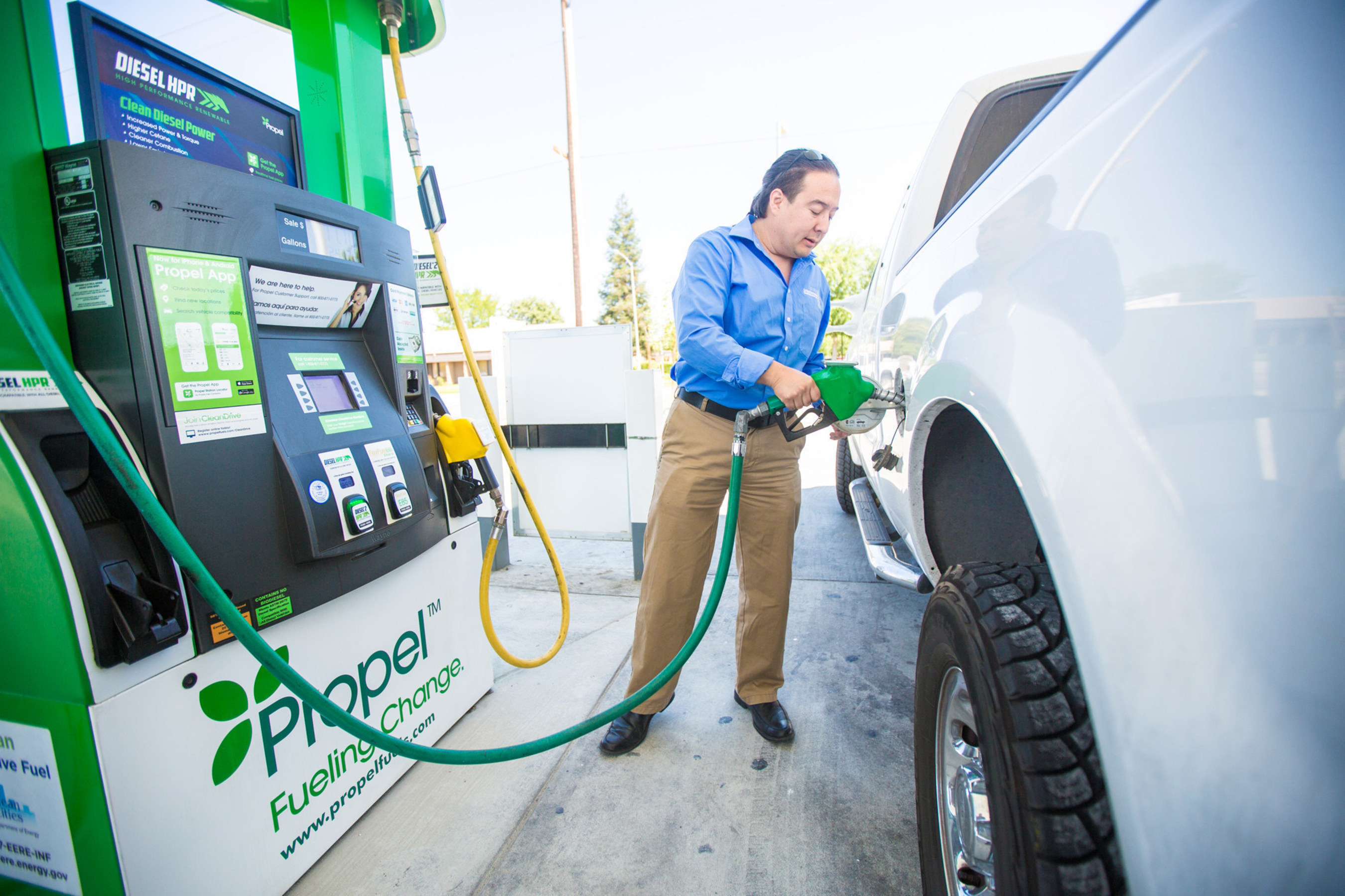 A driver fills a white pickup at a green Propel Diesel HPR dispenser.