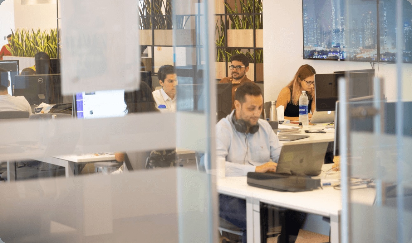 Property Finder employees working at desks in a glass-partitioned office