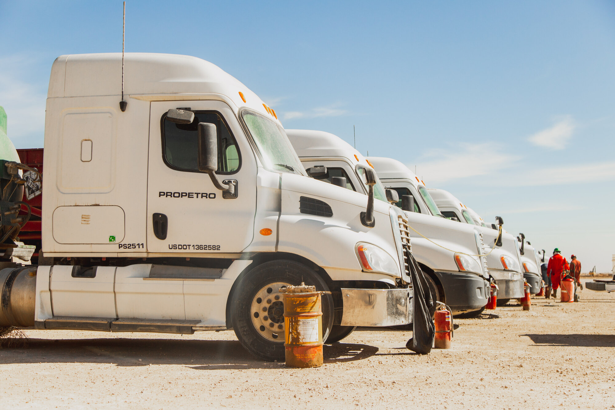 A row of ProPetro trucks parked at a dusty frac site