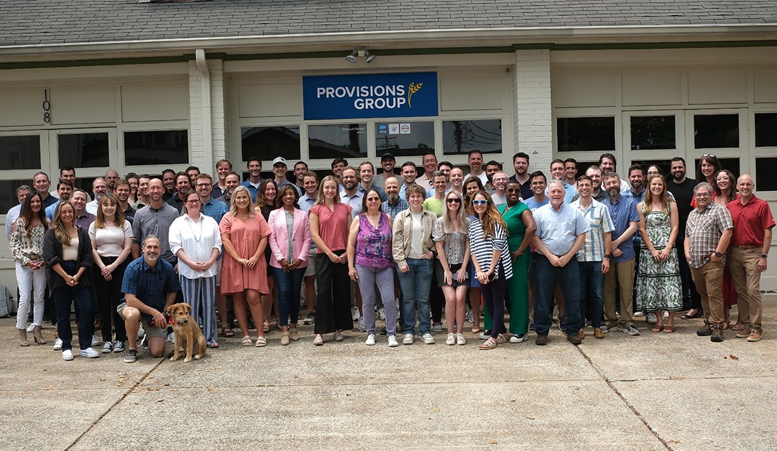 Provisions Group employees gathered outside the office at their 2024 all-hands meeting, with a dog in the front row
