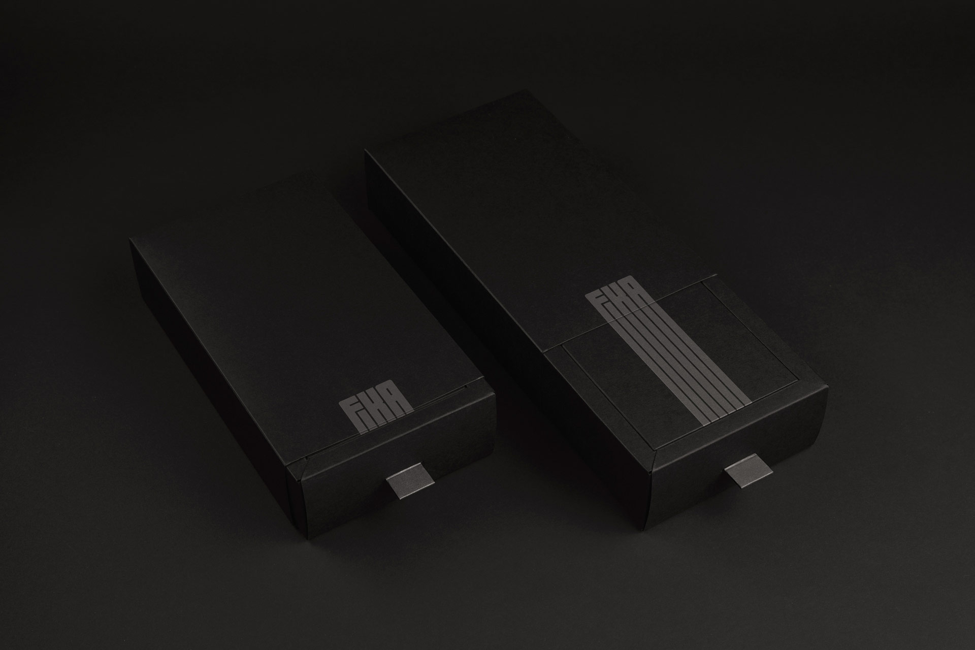 Two black Fika gift boxes showing the short and extended lettering as the packaging opens