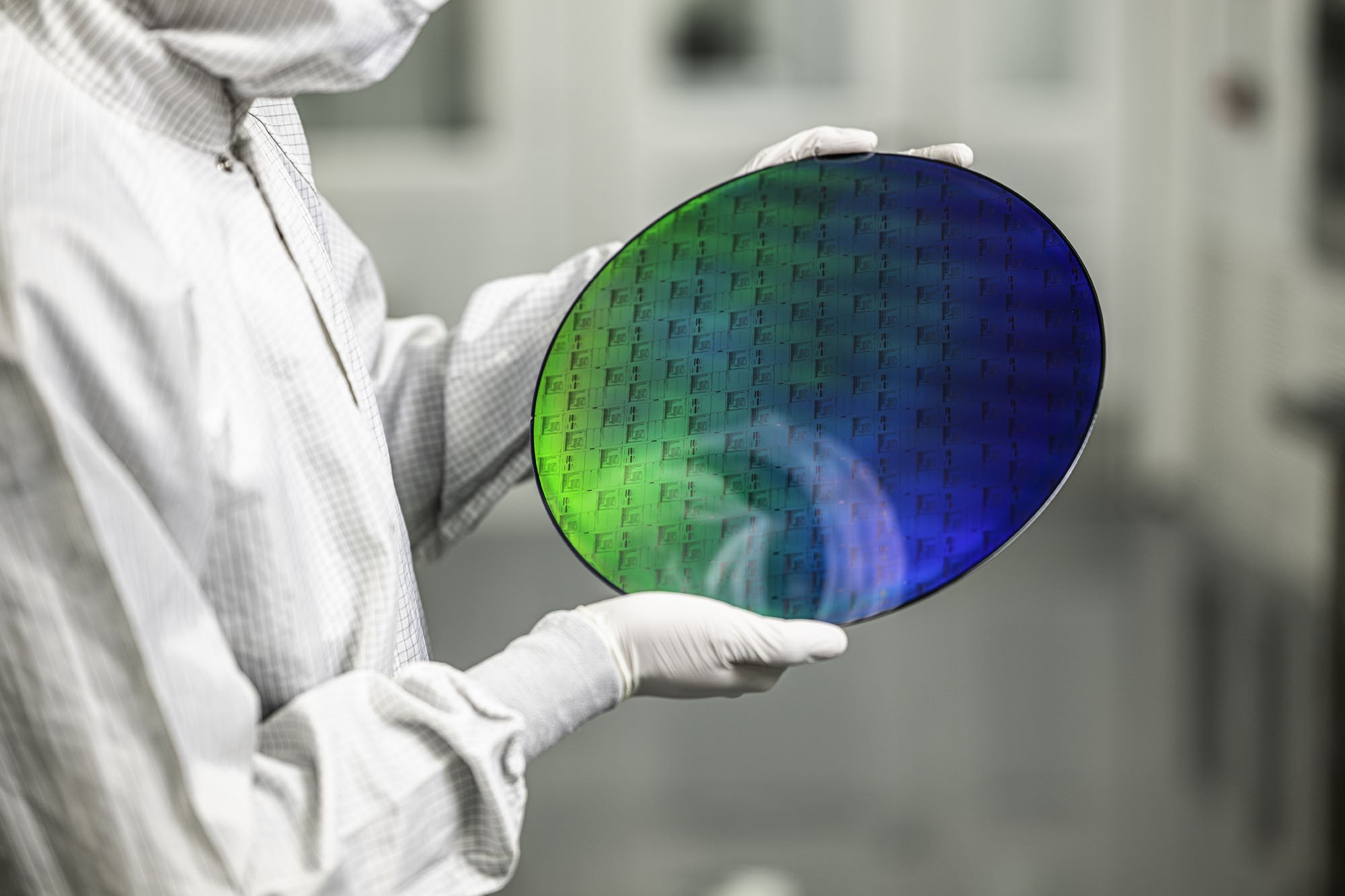 A cleanroom worker holds a patterned PsiQuantum photonic wafer