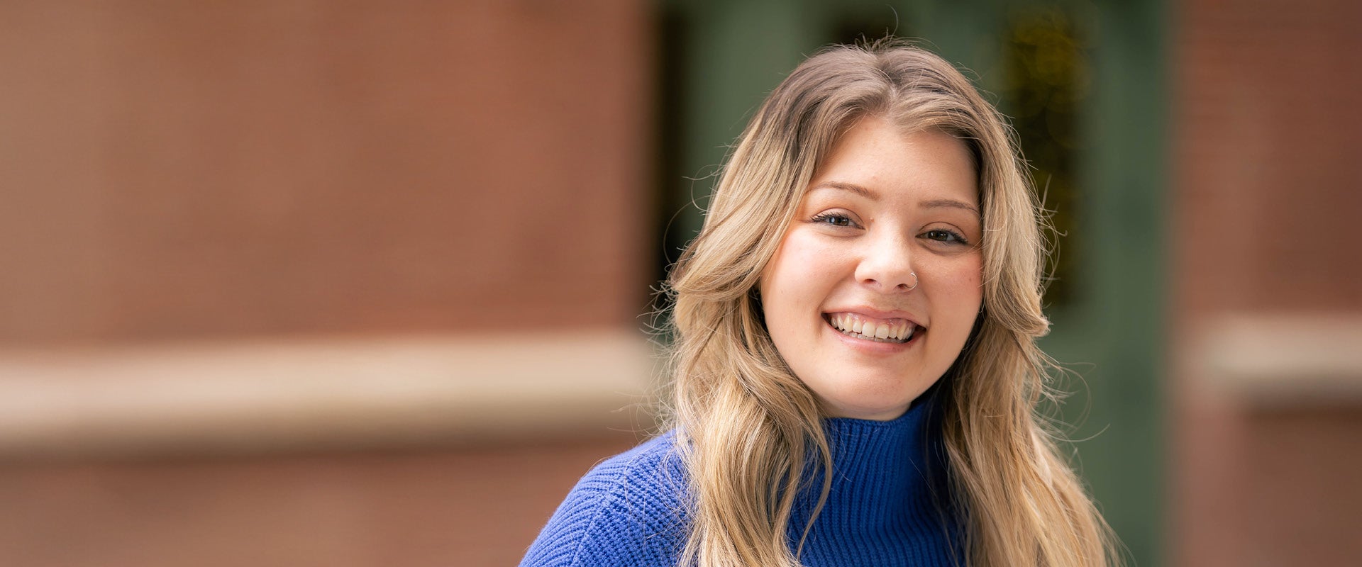 Katie, identified by PTC as living with PKU, smiling in a blue sweater