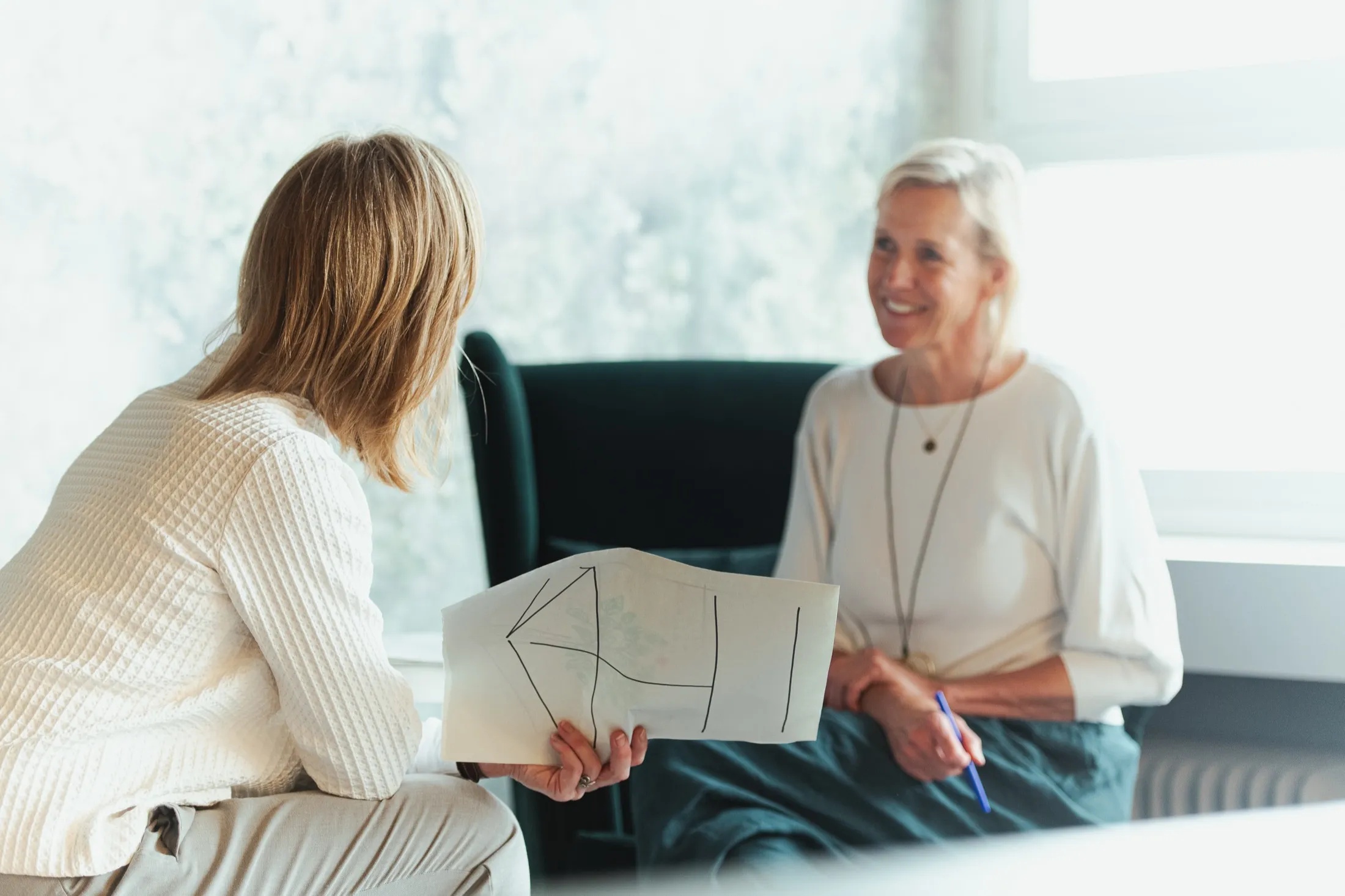 Two women discussing a hand-drawn plan at a Revival session