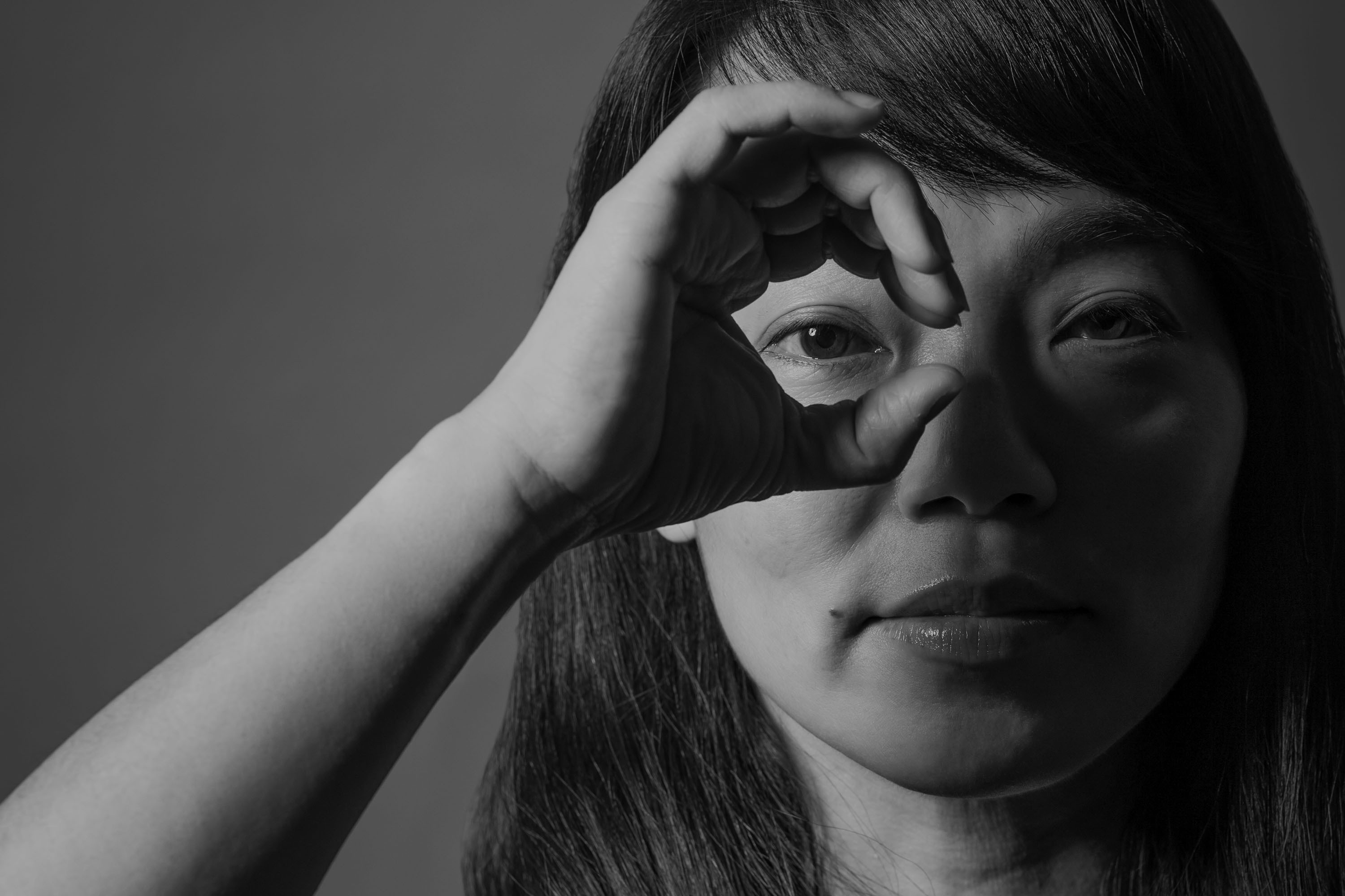 Black-and-white Purpose Unlimited campaign portrait of a woman looking through a circle formed by her hand