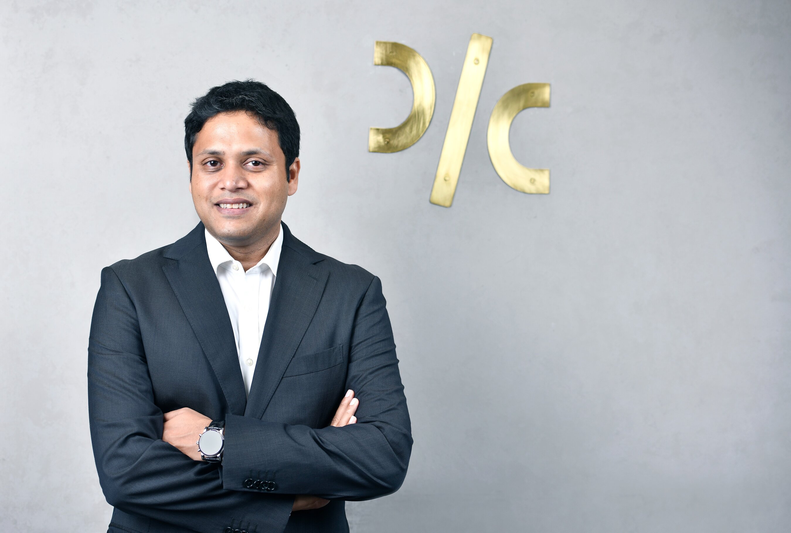 Pushkar Mukewar standing in a suit beside the Drip Capital emblem