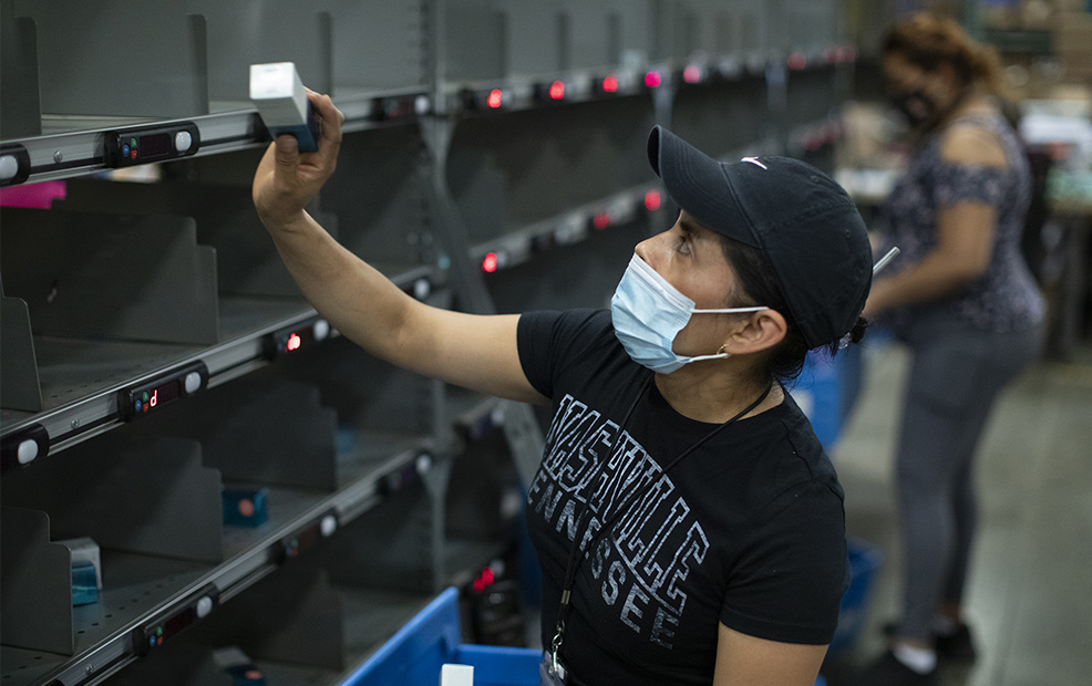 Warehouse worker using illuminated modules on a Lightning Pick put wall