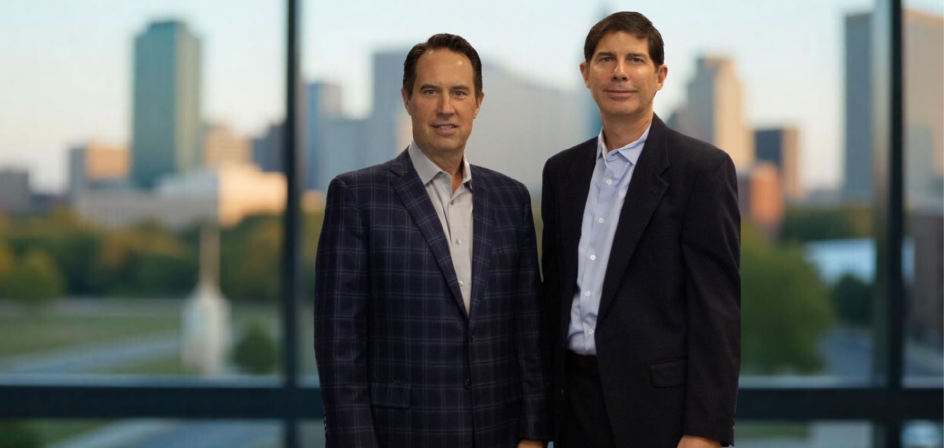 QAT Global co-founders Ken Bass and Rollie Stephens photographed with a city skyline behind them