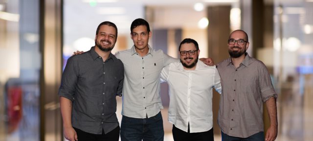 Four QAT Global team members standing together in an office
