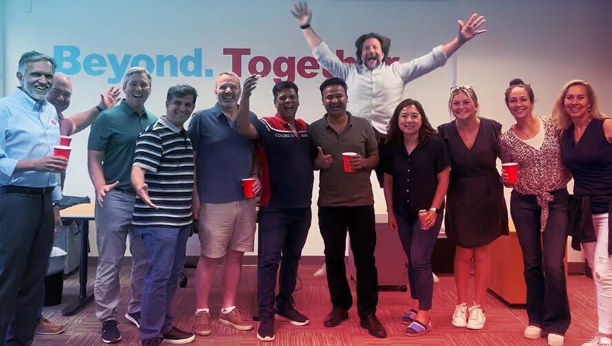 Members of the Qu team gathered in an office beneath the words Beyond Together