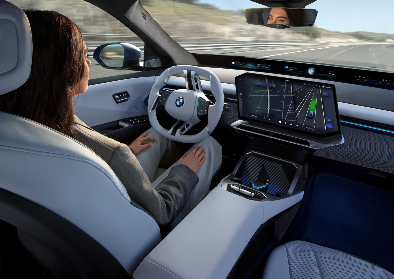 BMW iX3 promotional interior showing the driver, panoramic display and driver-assistance visualization