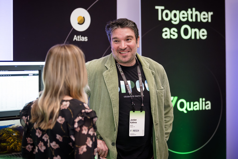A Qualia representative speaking with an attendee at the company's Together as One event booth