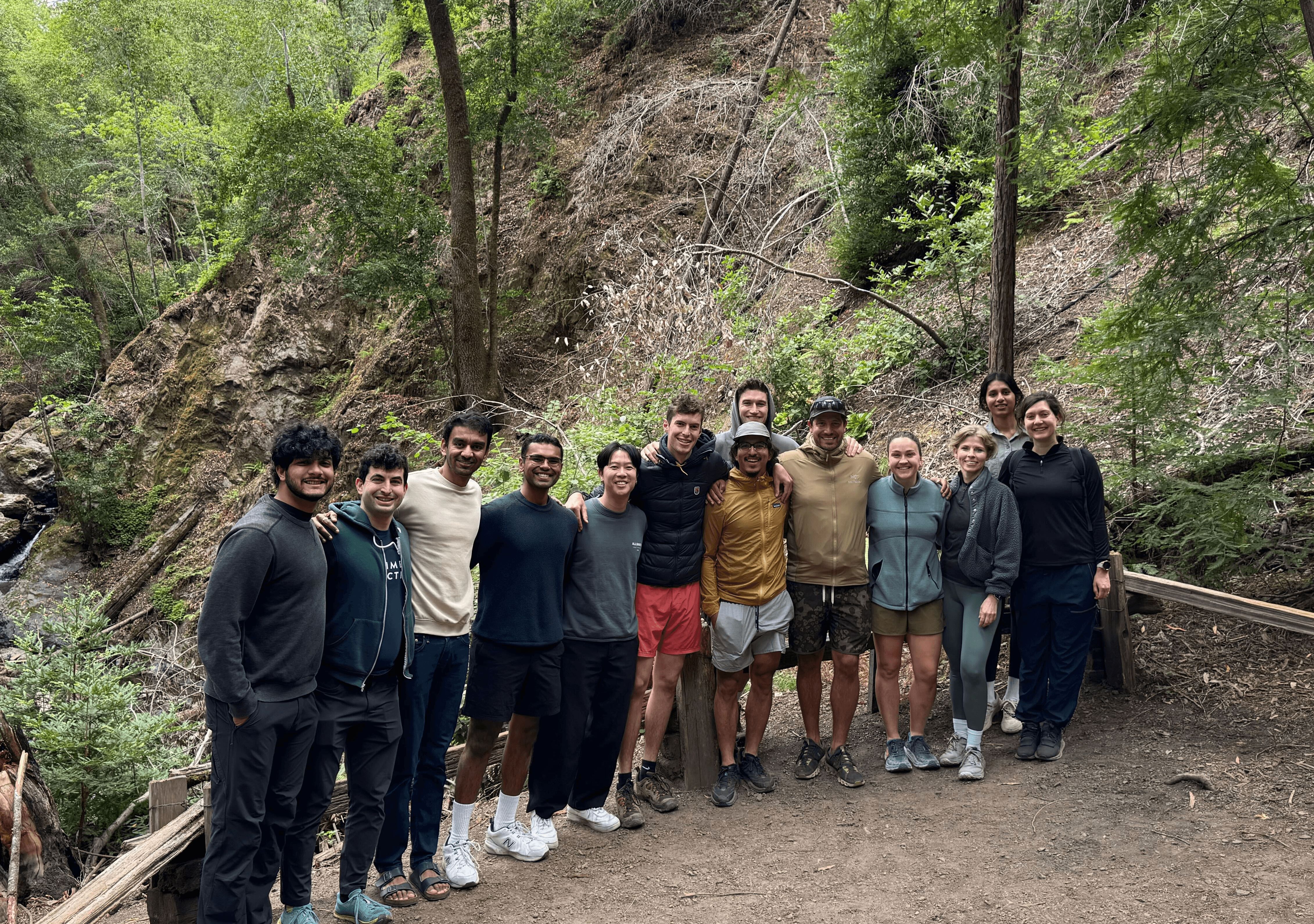 Members of the Quanta team standing together on a wooded trail