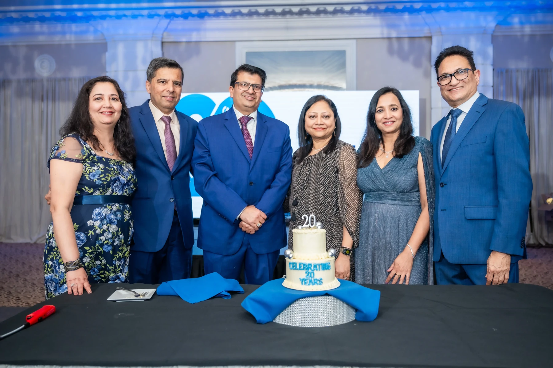 A group gathered around a Quantum Integrators twentieth-anniversary cake
