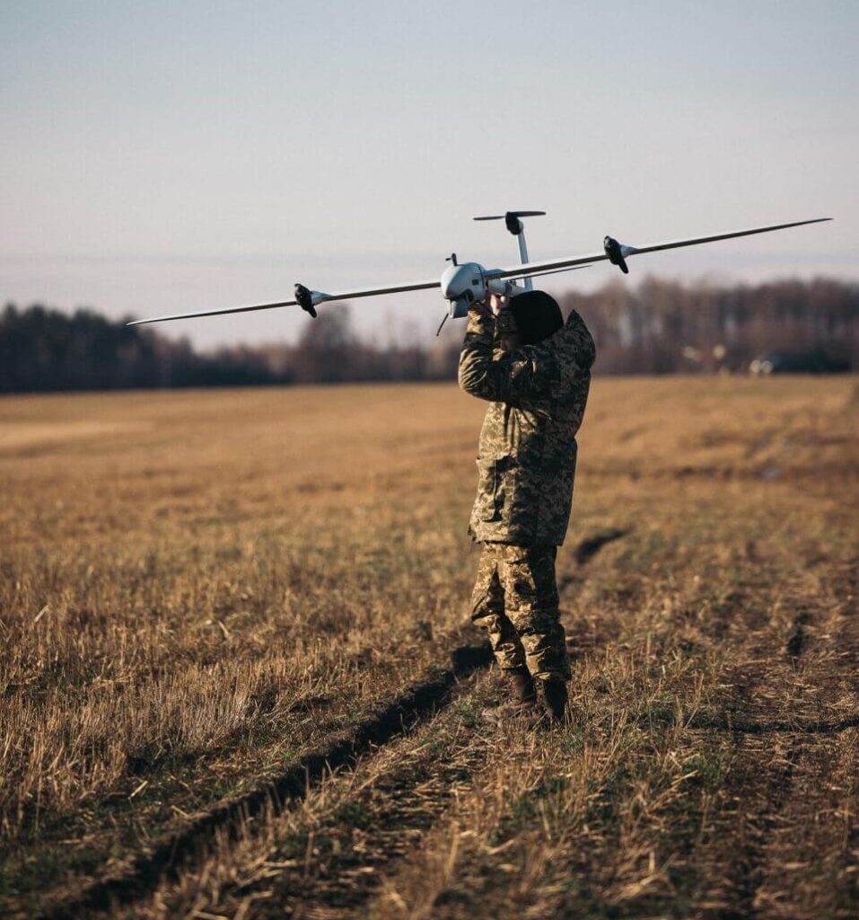 An operator carries a winged Quantum Systems drone across an open field