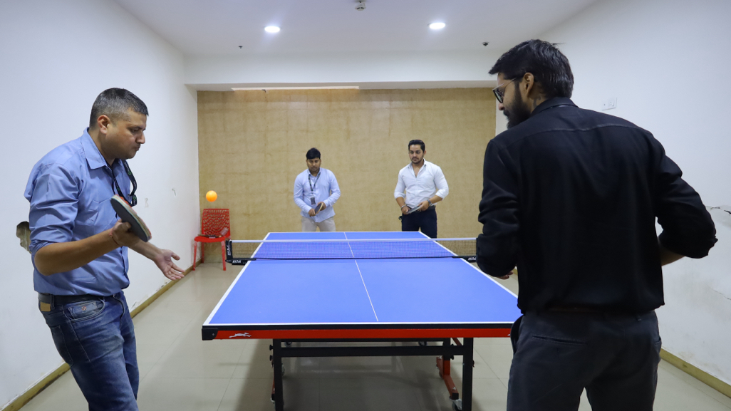 Four Quarks colleagues playing doubles table tennis in an office recreation room