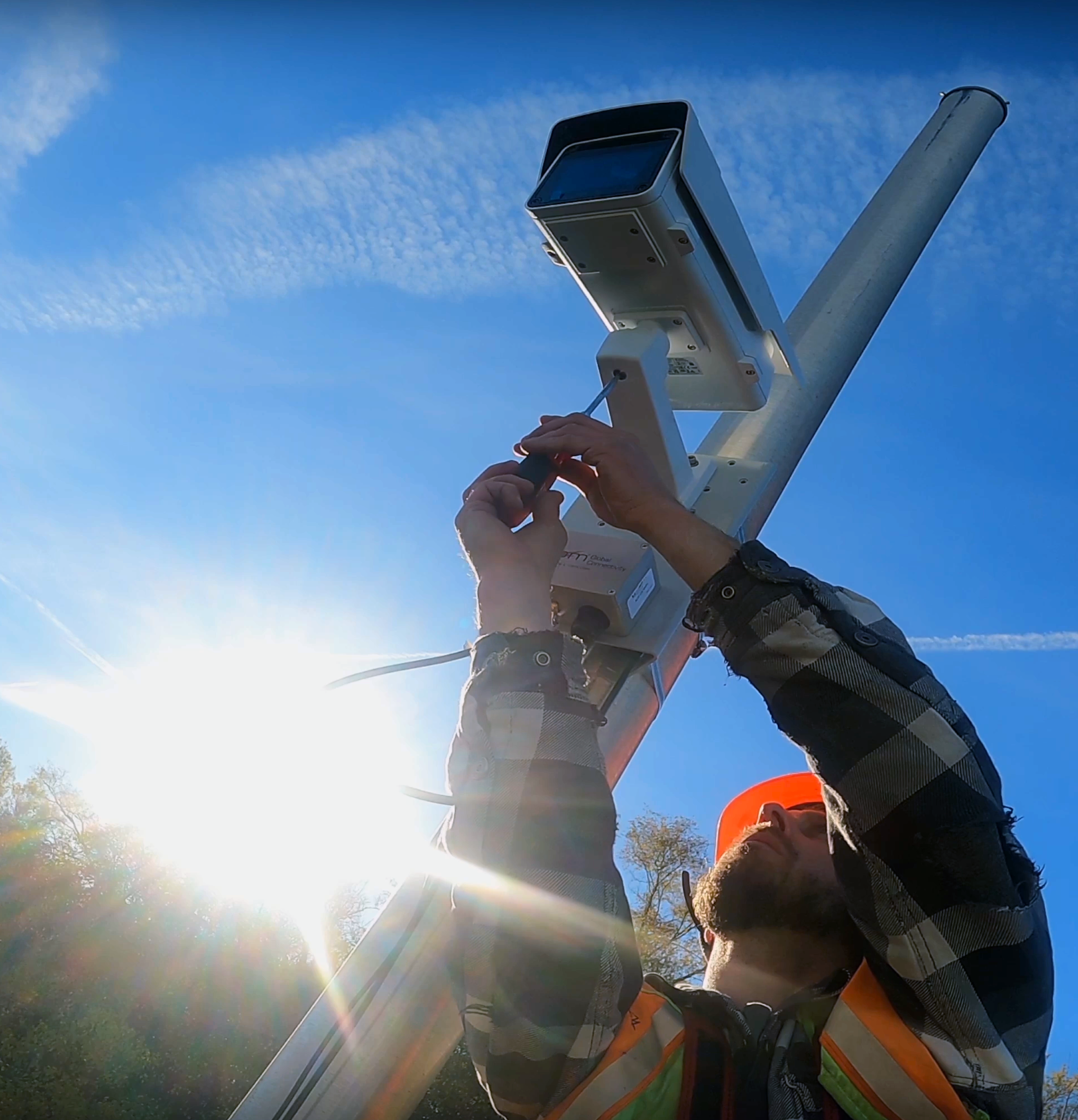 A technician secures a Quarterhill roadside camera to its mounting bracket