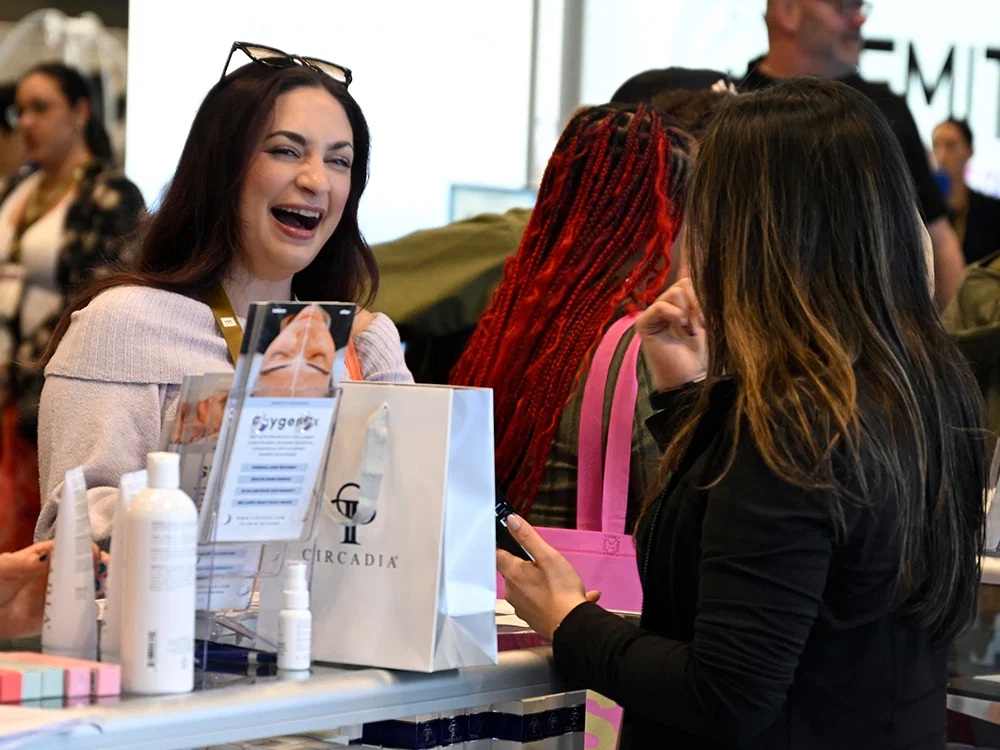 Exhibition visitors talking with a beauty-product representative across a display counter