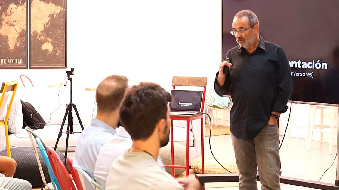 Quino Fernández addressing a seated workshop audience beside a presentation screen