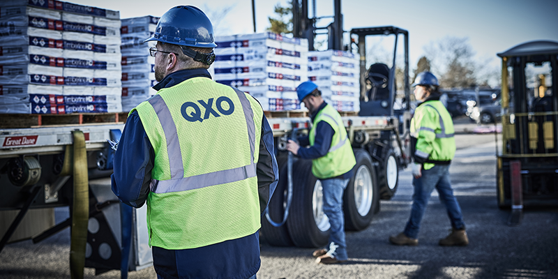 QXO branch employees working beside a truck loaded with building materials