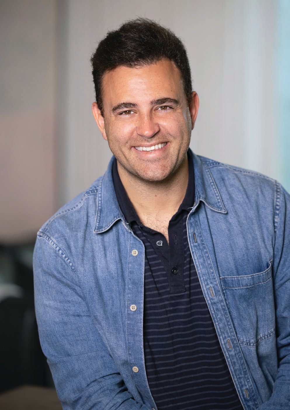 Raad Mobrem smiling in a denim shirt in an Intro press photograph