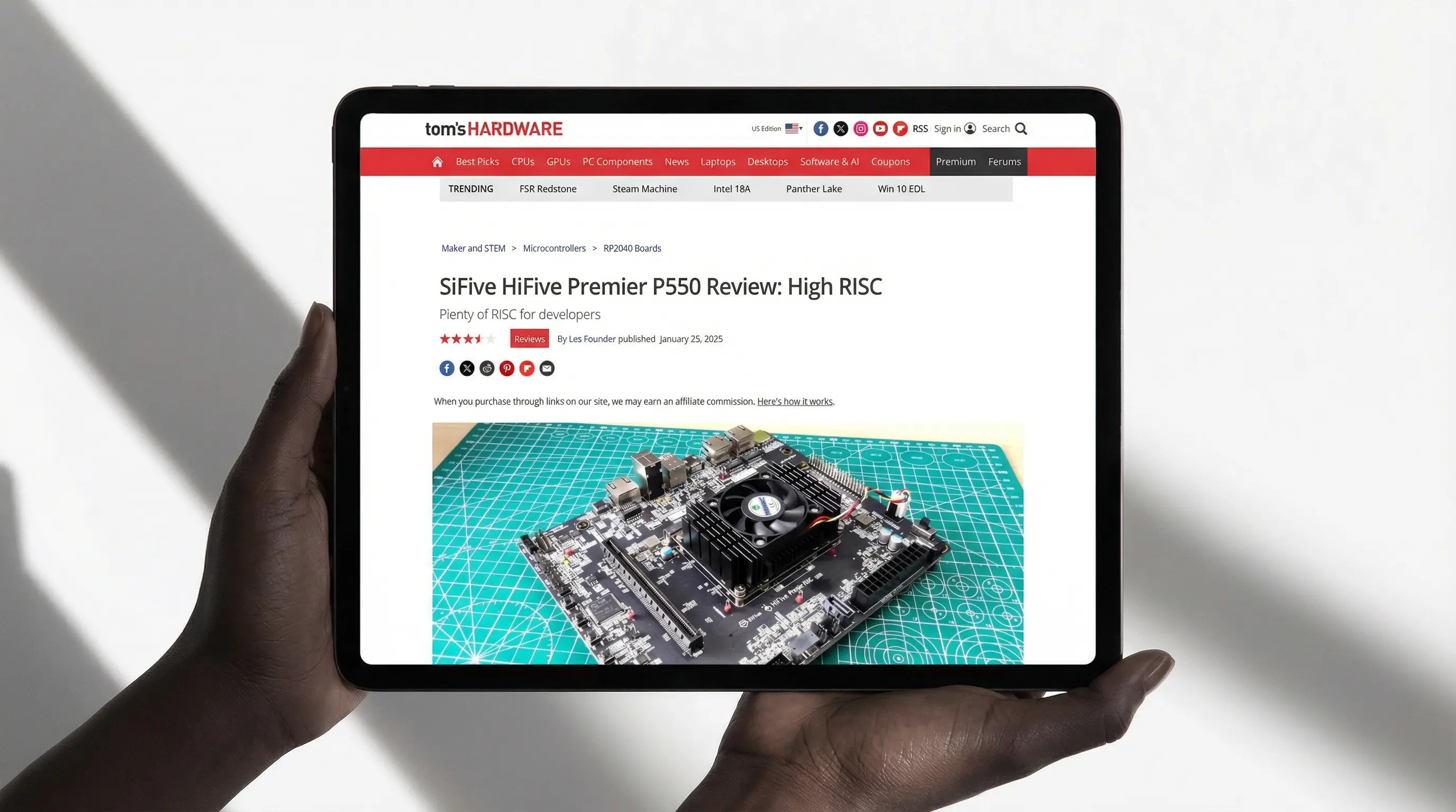 Hands holding a tablet displaying coverage of a SiFive computer board