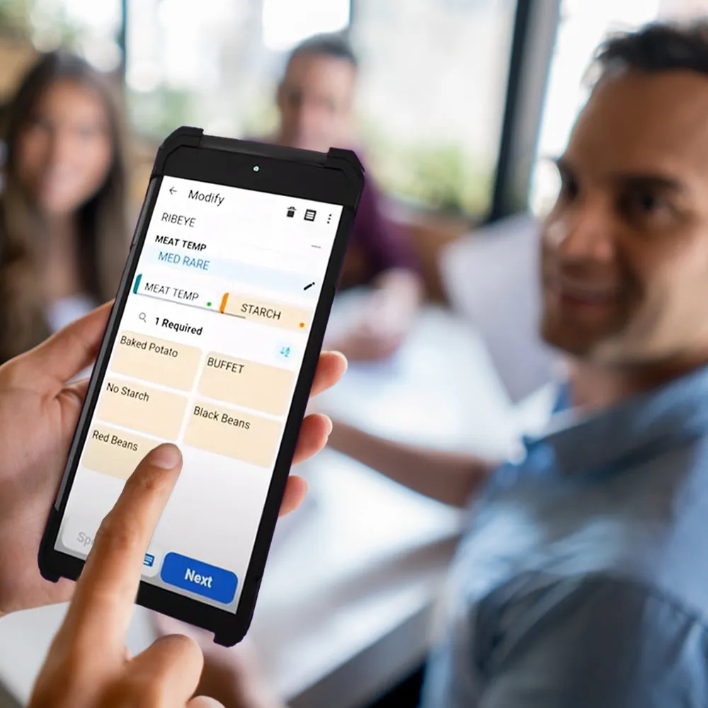 A person using a contemporary NCR Voyix restaurant handheld to choose meal options