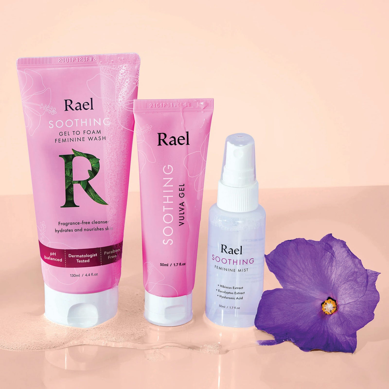 Rael feminine wash, vulva gel and feminine mist arranged against a peach background with a purple flower