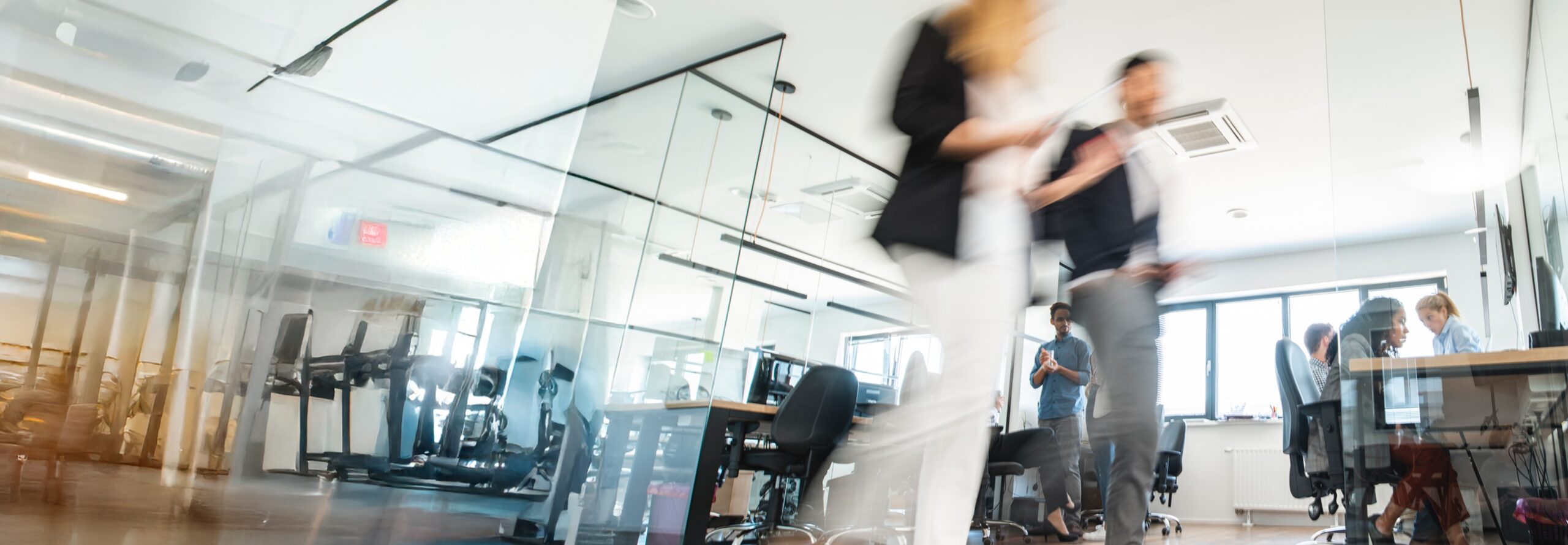 A bright office scene with people moving through a collaborative workspace