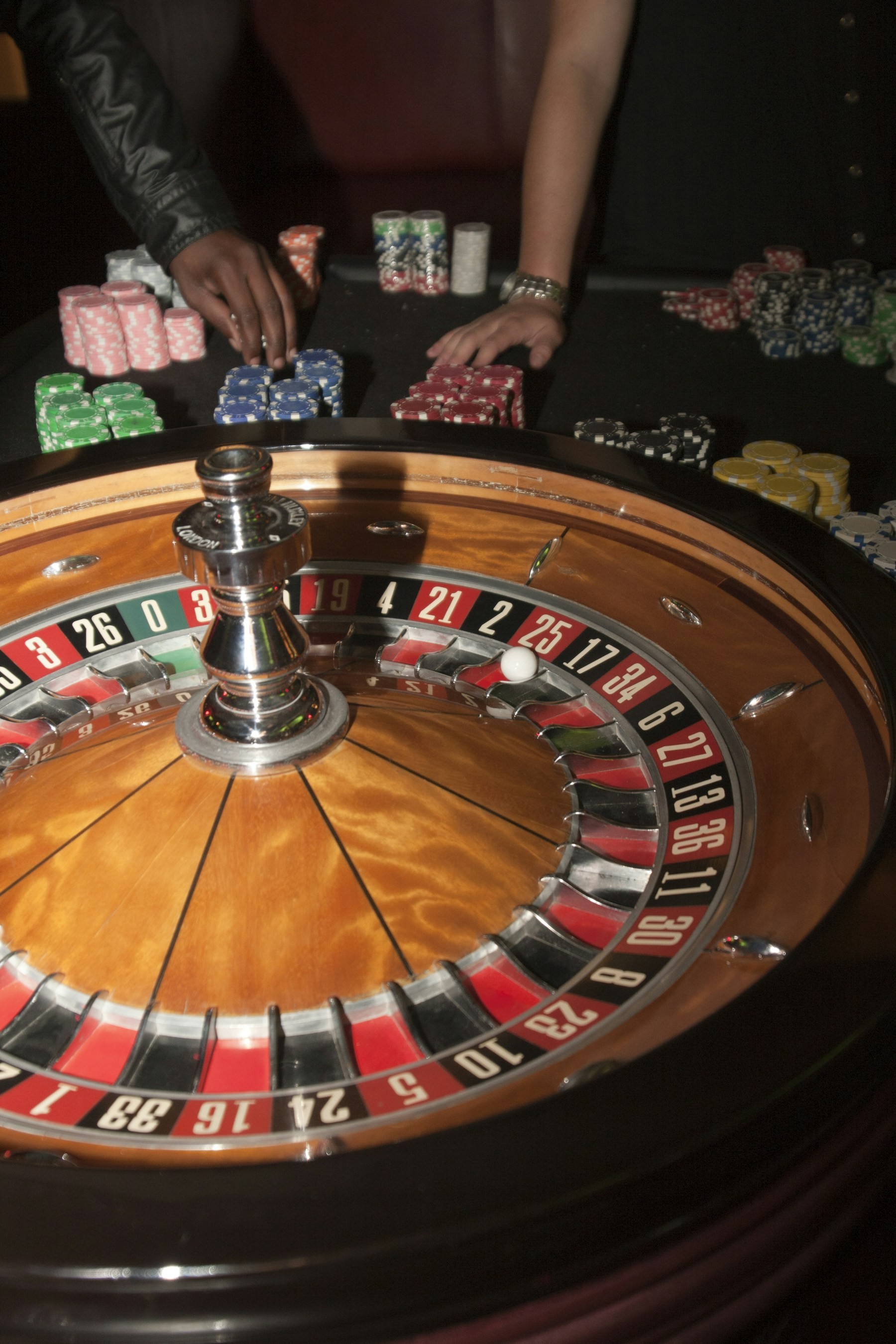 Roulette wheel with gaming chips and players’ hands