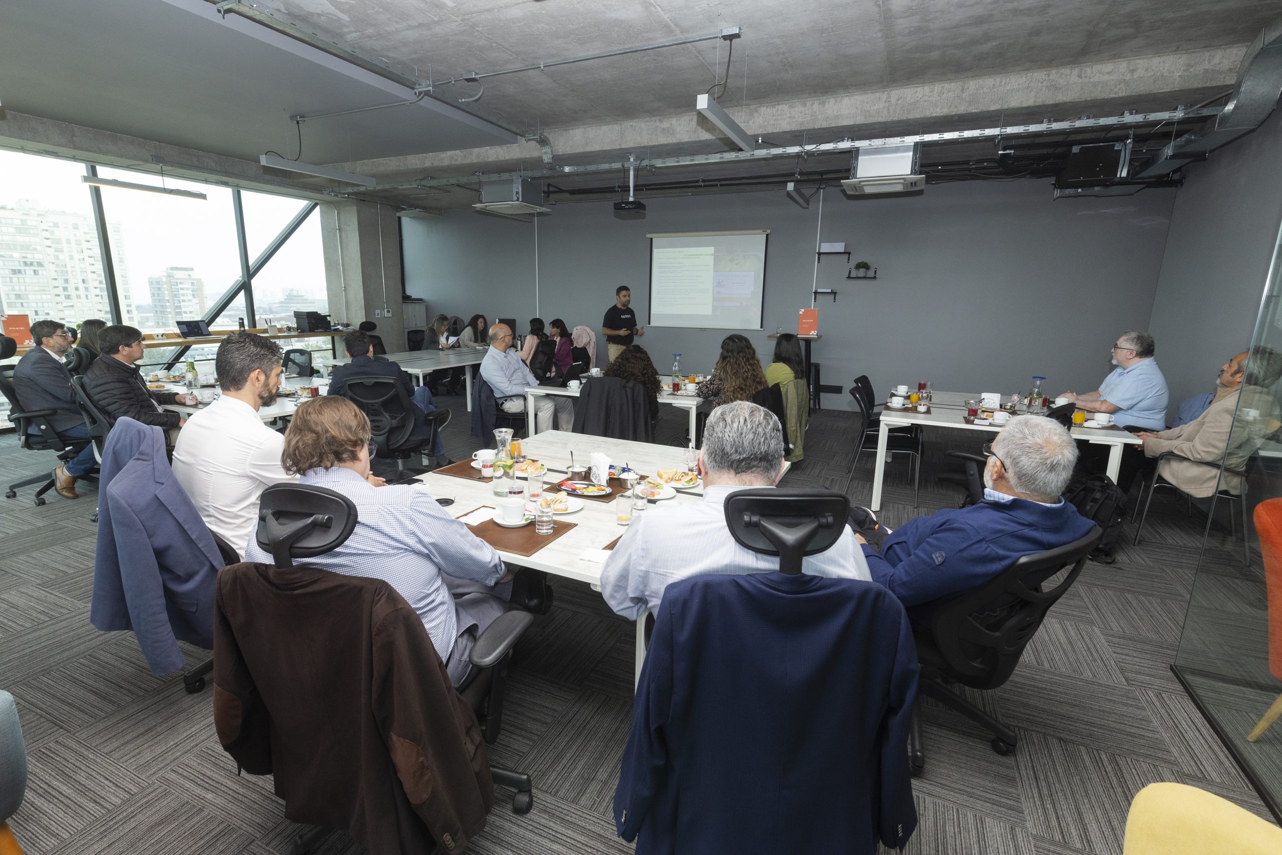 Raimundo Page addresses members gathered around tables at a Chiletec assembly