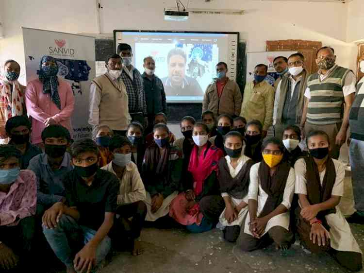 Students and teachers at Sanvid's school launch, with Raj Darji appearing on the classroom screen